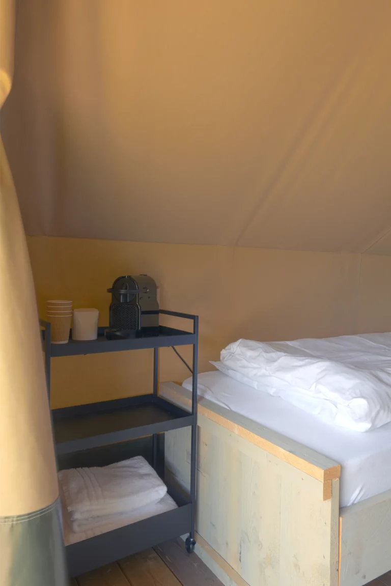 glamping tent met espresso machine en opgemaakt bed